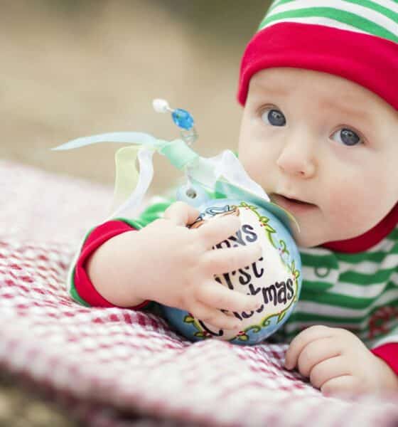 Beautiful Infant Baby On Blanket With Babys First Christmas Ornament.