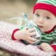 Beautiful Infant Baby On Blanket With Babys First Christmas Ornament.